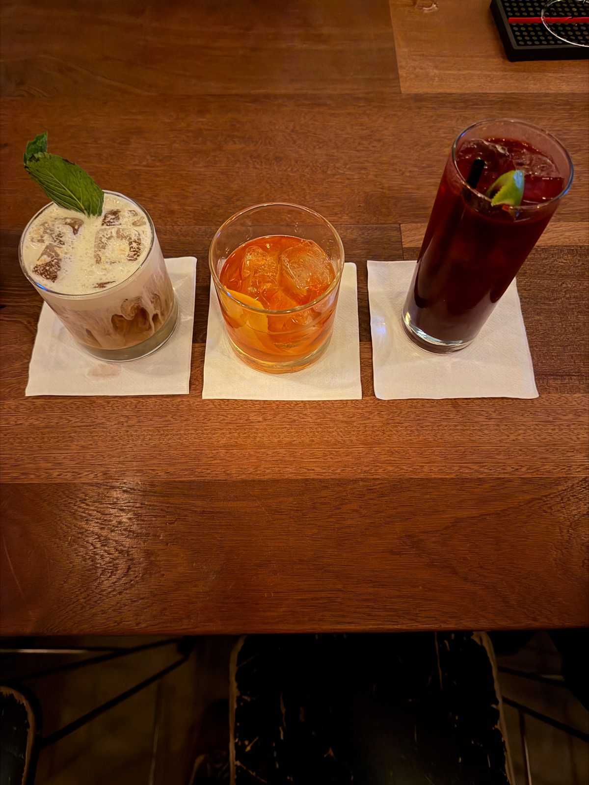 Three craft cocktails on a wooden bar