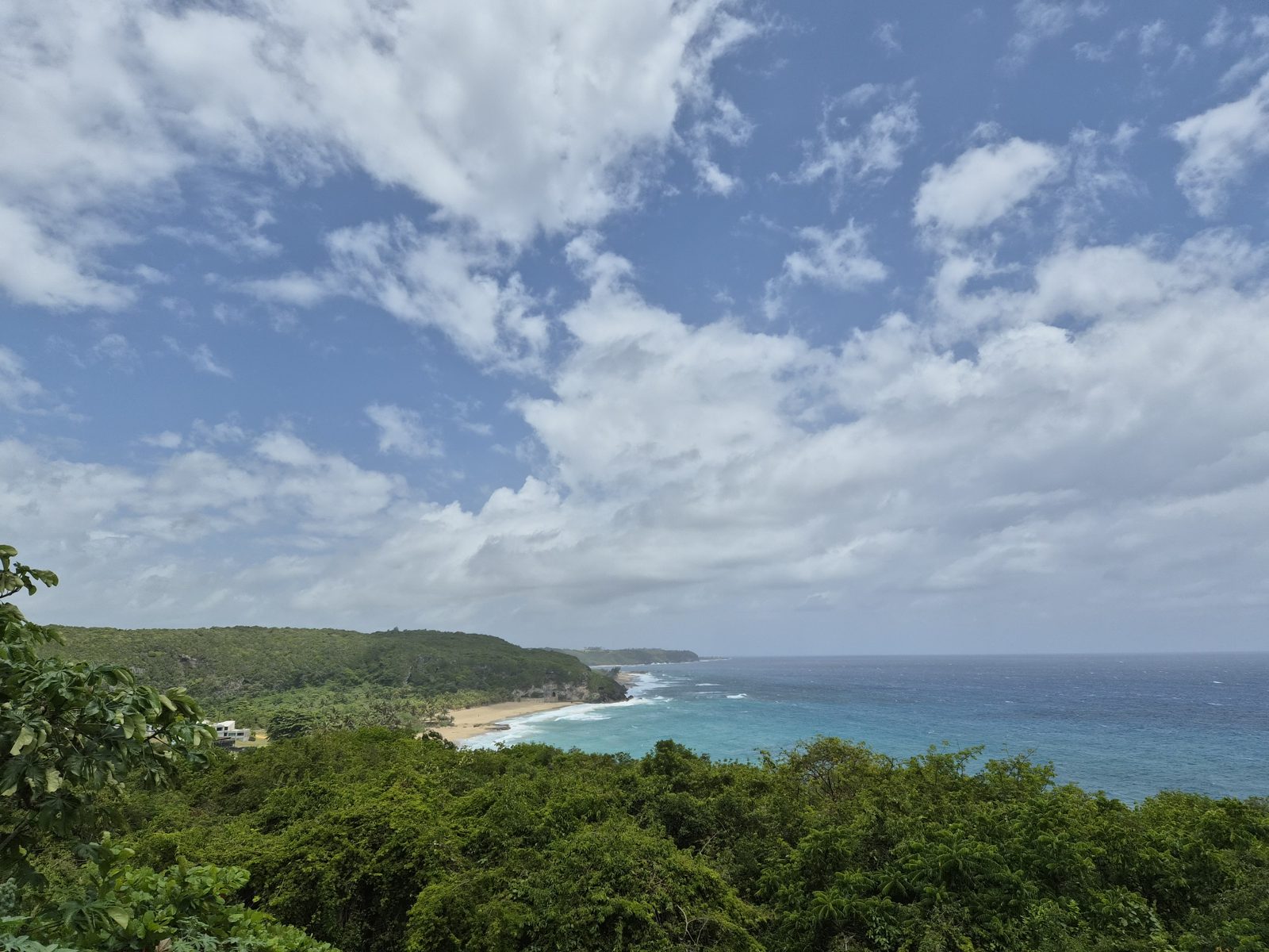 The northern coastline seen from a forested lookout under a sky of scattered clouds